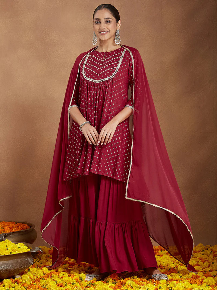 Woman in a maroon traditional outfit with a cape on a brown background